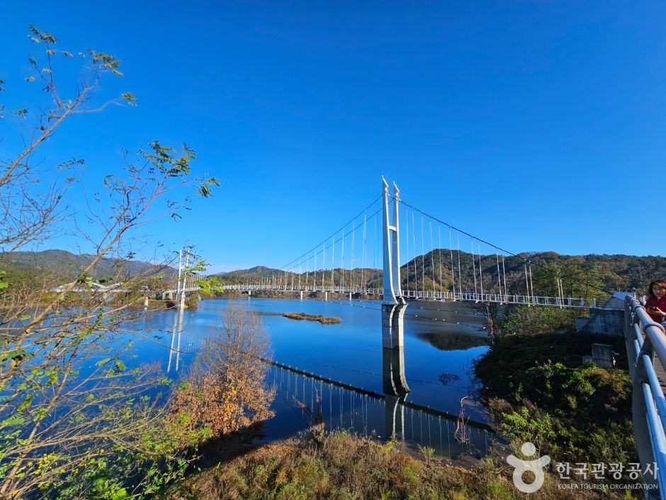 Buhang Dam Suspension Bridge with its white towers spanning the lake under a blue sky